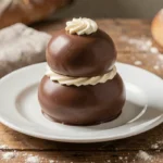 Religieuse au chocolat classique posée sur une assiette blanche dans une boulangerie artisanale, montrant sa taille et sa forme traditionnelle à deux choux superposés